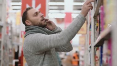 Genç adam, Evet mağaza vitrin ve ev Kimyasalları ürünler seçme--dan öğe alır. 4k