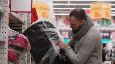 Mağaza raflarında öğesini seçerek genç adam istiyor güle güle Bebek Oto Koltuğu için kalite kontrol. 4k