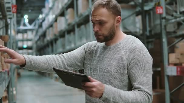 Joven usando tableta digital en el almacén, revisando la lista de productos en el supermercado y buscando artículos. 4K — Vídeo de stock