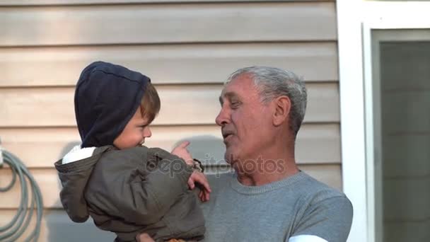 Opa en kleinzoon praten, glimlachen, plezier, op zoek naar camera buiten. Oude man jongetje aan kant te houden. 4k — Stockvideo