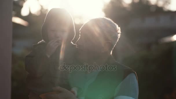 Grand-père tenant son petit-fils sur sa main. Petit garçon mangeant des baies, vieil homme regardant le gamin et riant. 4K 