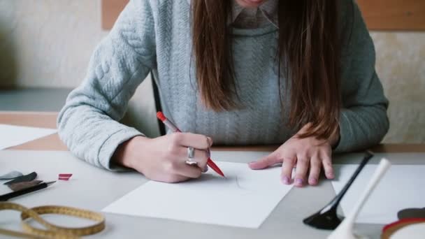 Mujer morena sentada a la mesa, sosteniendo lápiz y dibujo en el papel. Borra el boceto. Control deslizante a la izquierda. 4K — Vídeo de stock