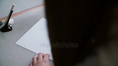 Arkadan görünüşü, topuk ve Tekstil örnekleri ile masada oturan kadın kroki çizim kağıt üzerinde. Kaydırıcıyı sola. 4k