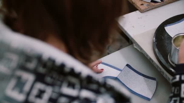 Jovem designer mulher vara dublerin de couro para futuros sapatos superiores. Manchas peça com cola e escova. Slider para a esquerda, 4K — Vídeo de Stock