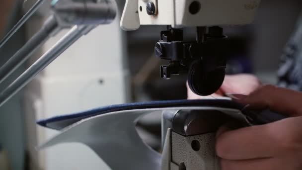 Close-up van vrouwelijke handen samen naaien twee stukken leer en textiel. Vrouw die werkt in de fabriek. 4k — Stockvideo