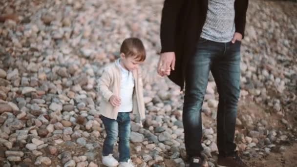 Baba ve oğul sahilde elele ve gün batımında kıyı yürüyüş. Birlikte vakit — Stok video