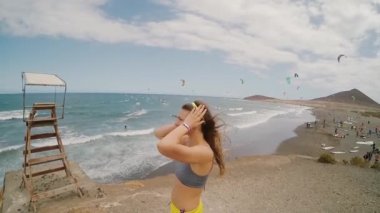 Rüzgarlı gün deniz kenarı deniz kenarında duran genç çekici kadın. Bir arka plan üzerinde kitesurfing için yer