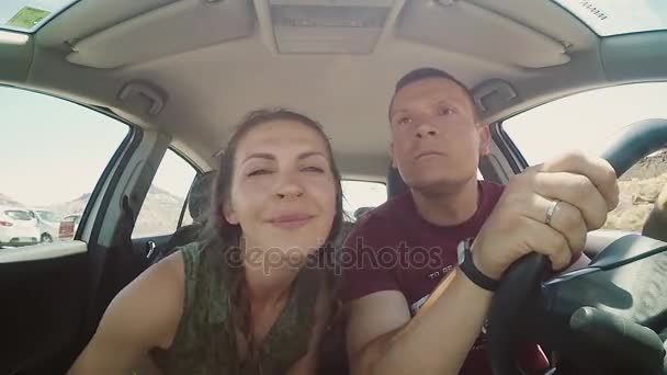 Casal jovem viajando no carro através das rochas. Homem e mulher se divertem, fazendo cara engraçada na estrada juntos — Vídeo de Stock