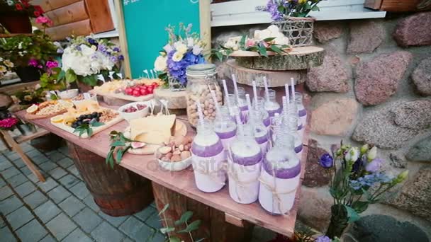 Cheese table with other snacks outside. Flowers, slices cheese, nuts, eggs, drinks and tomatoes on a wooden board. — Stock Video