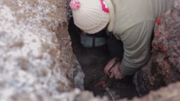 Hombre de pie en un agujero en la tierra y hacer la reparación del sistema de agua. Fontanero con llave extendida instalando un grifo . — Vídeos de Stock