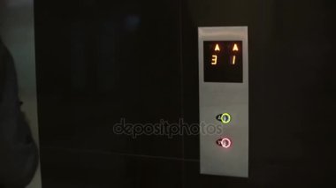 Kadın Asansör ve Dur düğmesine basın. Kadın ofiste ayakta ve smartphone, kullanarak birine çağırır.