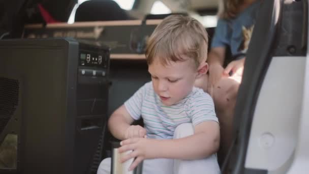 Χαριτωμένο μικρό αγόρι που κάθεται μέσα στο αυτοκίνητο. Η οικογένεια μετακομίζει στην νέα διαμερίσματα, να μεταφέρουν τρόφιμα στις μεταφορές. — Αρχείο Βίντεο