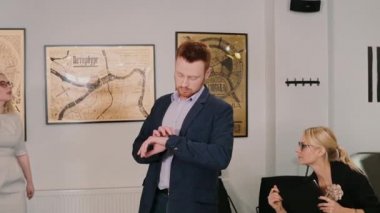 Genç modern ofisine gidiyor ve akıllı nöbette arıyor adam. Erkek yeni bir teknoloji kullanır. Ağır çekim.