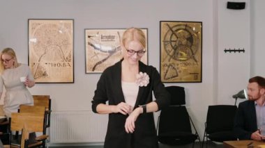 Bir yandan giyen onun smartwatch kullanarak tasarım kadın ofis üzerinde. Gülümseyen kız yeni teknoloji ile çalışma.