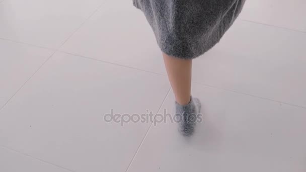 Крупный план женщины в носках и длинном свитере, идущей по комнате. Куртка падает на пол . — стоковое видео