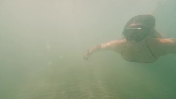 Glückliche junge Frau, die mit Maske unter Wasser schwimmt. Mädchen tauchen auf einer Oberfläche auf und verbringen Zeit am Strand. Zeitlupe. — Stockvideo