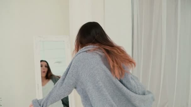 Gelukkig meisje in pyjama spinnen in de buurt van de spiegel. Jonge vrouw kijkt naar de reflectie en glimlach. Slow motion. — Stockvideo