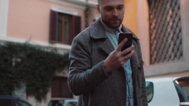 Şehirde smarphone app kullanarak mesaj sms, genç adam. Yakışıklı işadamı dokunmatik ekran teknolojisini kullanarak gülümseyen.