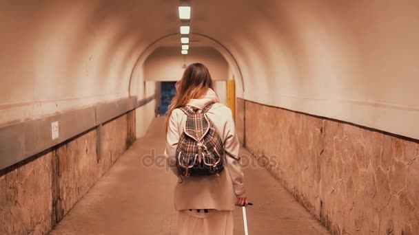 Joven mujer caminando por el túnel llevando la maleta. Chica con mochila llega a la ciudad y va en el hotel . — Vídeo de stock