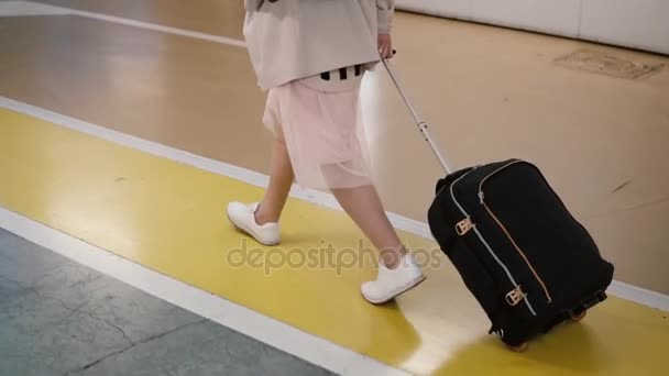 Junge, stylische Reisende, die mit einem Koffer durch die Flughafenhalle läuft. Frau kommt in den Urlaub. — Stockvideo