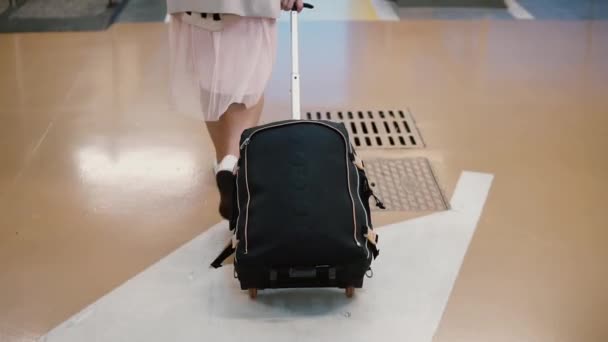 Νεαρή γυναίκα ταξιδιώτης περπατώντας μέσα από το αεροδρόμιο με τη βαλίτσα. Γυναίκα πηγαίνει πέρα από το χώρο στάθμευσης και βγαίνει στην πόλη. — Αρχείο Βίντεο