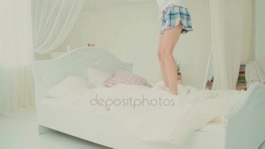 Mutlu taze kadın yatağında sabah atlama Pijama giyiyor. Güzel kız eğleniyor. Ağır çekim.