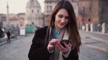 Şehirde yürüyüş ve smartphone kullanarak genç mutlu bir kadın. Kız Gözat Internet, Roma, İtalya'da tatil harcama.