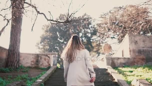 Junge modische Frau läuft die Treppe hinauf. Stilvolles Mädchen beim Spaziergang in der frühlingshaften Altstadt, helles Sonnenlicht am Morgen. — Stockvideo