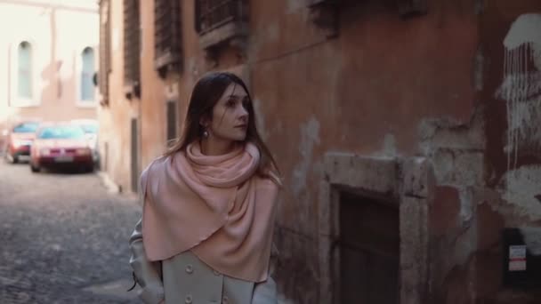 Una mujer joven y bonita caminando sola por el callejón. Chica yendo en la calle lateral y pensando, mirando a su alrededor . — Vídeo de stock