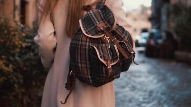 Back view of young tourist woman with backpack walking down the street. Pretty girl spending vacation in Europe. — Stock Video