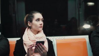 Metro treninin smartphone kullanarak çekici kız. Genç kadın Gözat dokunmatik ekran teknolojisi ile Internet.