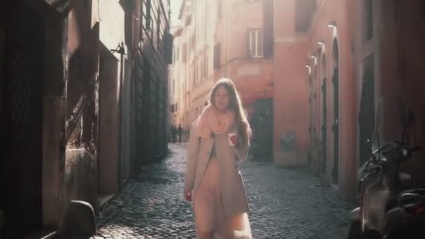 Stilvolle junge Frau, die morgens allein durch die Gasse geht. Mädchen geht in Seitenstraße und genießt die Zeit draußen. — Stockvideo