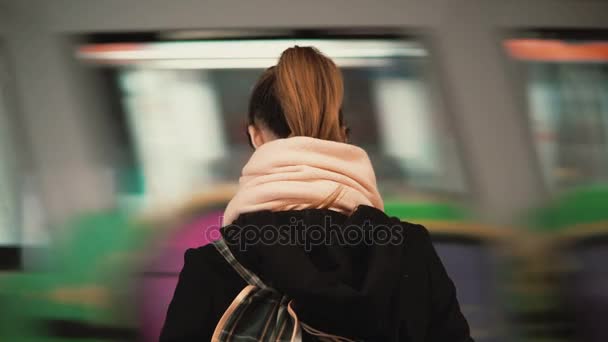 Mujer joven de pie en la plataforma del metro en el fondo del tren que pasa. Chica esperando metro para ir a trabajar . — Vídeos de Stock