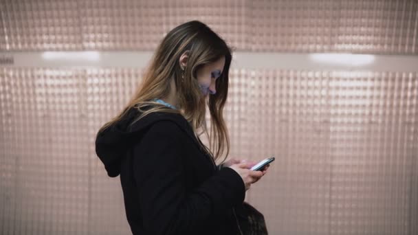 Mujer morena de pie en la plataforma del metro y el uso de teléfono inteligente. Chica navegando por Internet mientras espera el tren . — Vídeo de stock