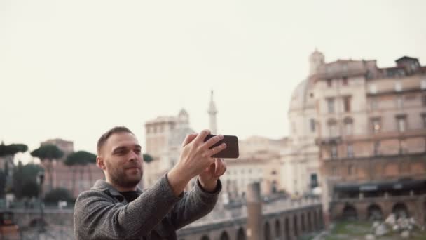 Touristenmann macht Selfie-Fotos vor dem Hintergrund des Stadtzentrums von Rom, Italien mit seinem Smartphone, lächelnd. — Stockvideo