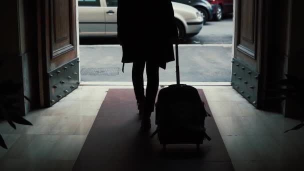 Back view of businesswoman walking with a suitcase in the tunnel. Girl goes out of entrance in the city. Slow motion. — Stock Video