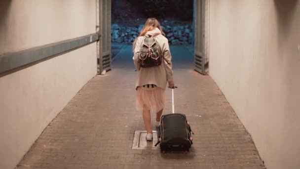 Νεαρή γυναίκα περπατώντας μέσα από το τούνελ, κουβαλώντας τη βαλίτσα. Κορίτσι με σακίδιο, περιπάτους στην πόλη, που ταξιδεύουν. Αργή κίνηση. — Αρχείο Βίντεο