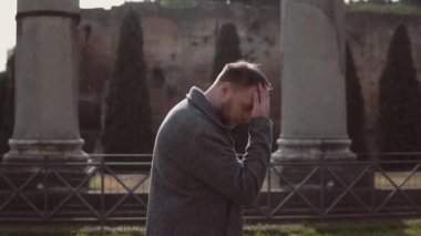 Yakışıklı adam, Roma, İtalya, kalıntıları üzerine yürür. Adam saç çıkıyor, Roma Forumu mimarisini araştırıyor. Ağır çekim.