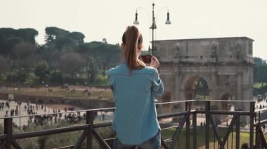 Genç kadın Constantine kemer onun smartphone Roma, İtalya ile güneşli bir günde çekiyor. Ağır çekim.