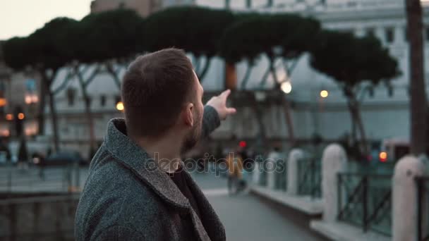 저녁에 이탈리아에서 로마의 중심에서 로마 명소를 고려 하 고 가리키는 잘생긴 관광 남자. — 비디오
