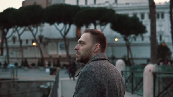 Ein gutaussehender mann betrachtet abends die sehenswürdigkeiten im zentrum von rom in italien, schaut sich um und genießt die fahrt. Zeitlupe. — Stockvideo
