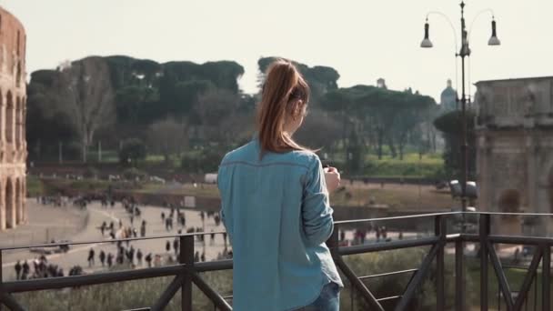 Turystyczna brunetka kobieta bierze Zdjęcia Łuk Konstantyna i withsmartphone Koloseum w Rzymie, Włochy. Zwolnionym tempie. — Wideo stockowe