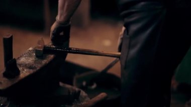 Demirci smithy örs üzerinde çalışıyor. Adam sıcak kırmızı metal su ile kova içine koyar. El yapımı ürün.