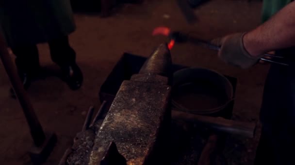 Un herrero forjando una herradura con un martillo sobre yunque en el taller. Hombre trabajando con metal rojo caliente . — Vídeo de stock