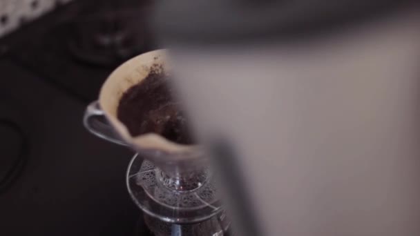 Close-up beeld van chemex koffiezetapparaat. Man met behulp van filters voor het maken van koffie, giet water uit een theepot. — Stockvideo