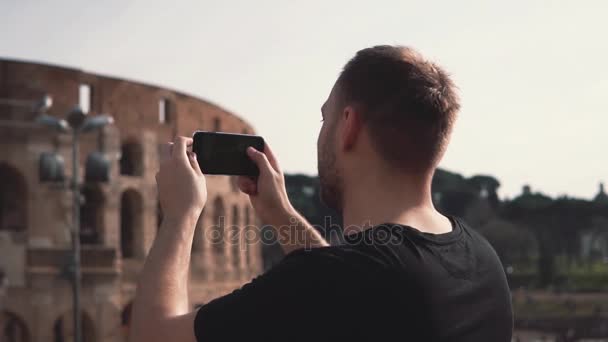 Hombre guapo turista visitando Roma, Italia tomar fotos del Coliseo. Paisaje con turistas en el fondo. Movimiento lento . — Vídeos de Stock