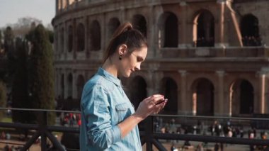 Genç kadın, Roma, İtalya onun smartphone biraz üzülmüş Colosseum, arka planı kullanır. Ağır çekim.