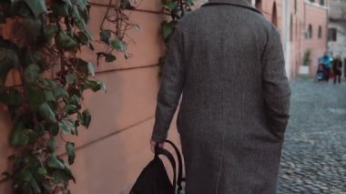 Akşamları ile eski street yürüyüş sırt çantası modaya adam. Turist new şehri keşfetmek erkek. Ağır çekim.