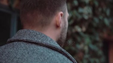 Arkadan Görünüm şık gencin akşam şehirde yürüyüş. Sakallı erkek eski caddenin gidiyor. Ağır çekim.