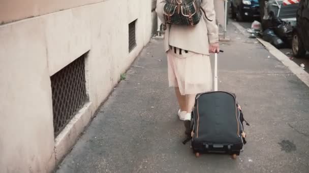 Mujer joven con maleta y mochila recorriendo el edificio de la ciudad. Chica con equipaje moviéndose a un nuevo lugar . — Vídeos de Stock